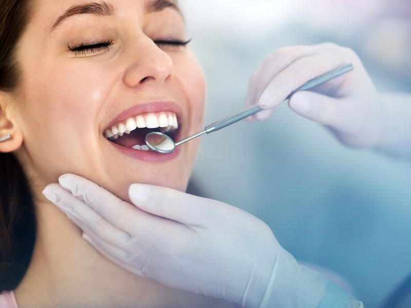 A dentist examines a patient with a mirror
