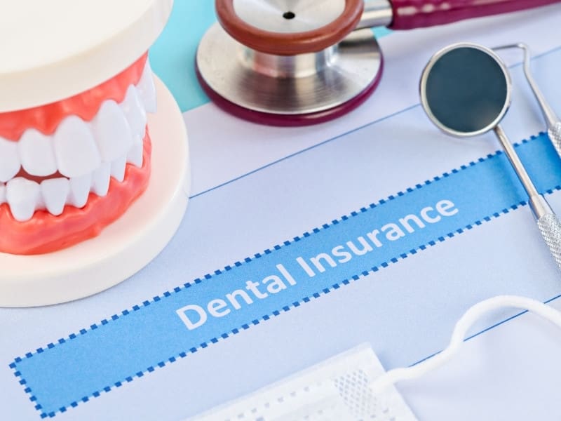 A form with the inscription "Dental insurance", a dummy jaw and dentist's instruments.